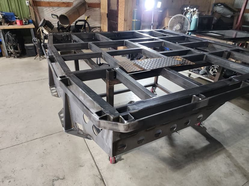 Welded steel frame on wheels in a workshop with tools and equipment in the background.