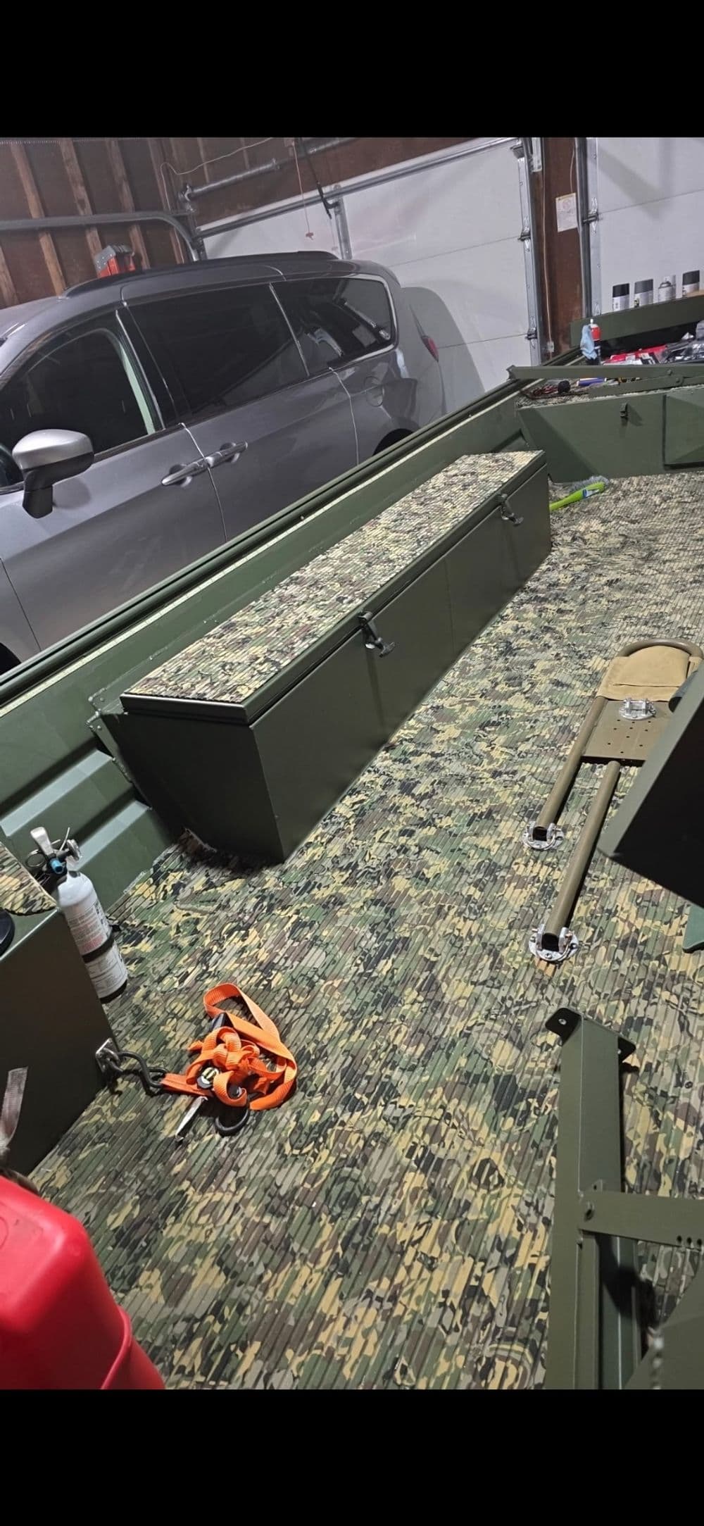 Interior of a camouflage-patterned boat, featuring storage compartments and fishing gear.