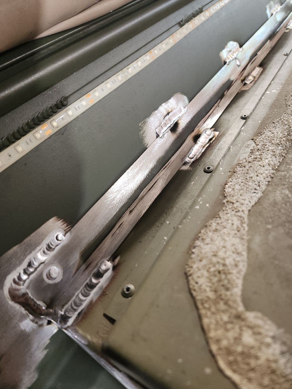 Close-up of metal surface with welding seams and sand texture, showcasing industrial details.
