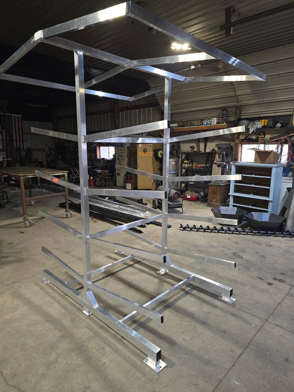 Aluminum rack structure in a workshop with multiple shelves for storage and organization.