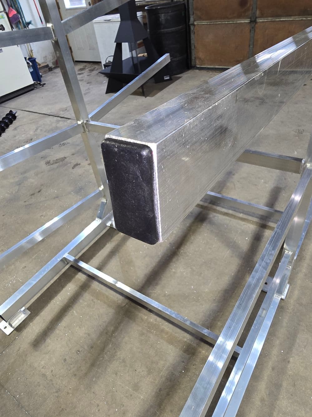 Aluminum rectangular beam on a metal frame in a workshop setting.