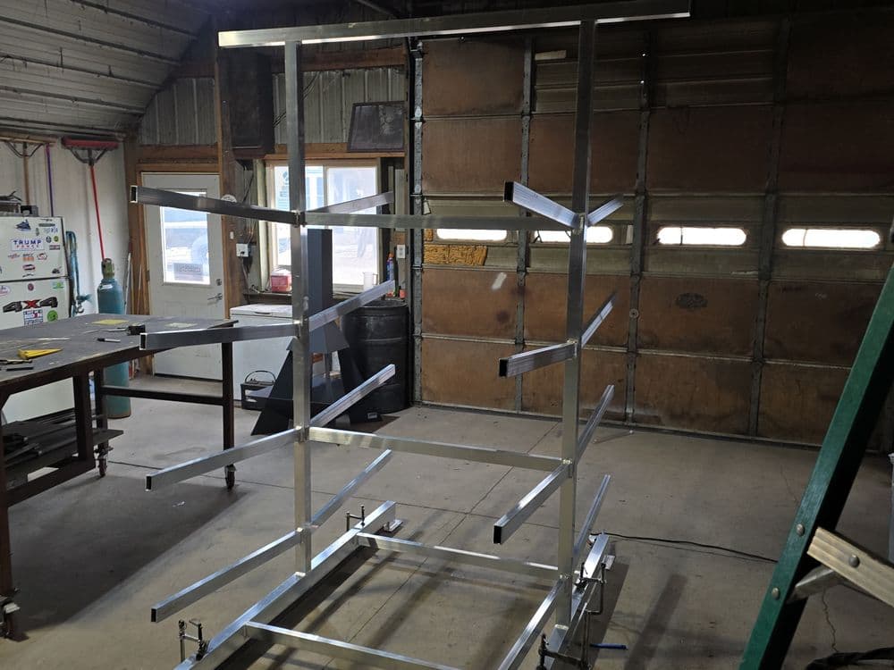 Aluminum storage rack structure in workshop with tools and garage door background.