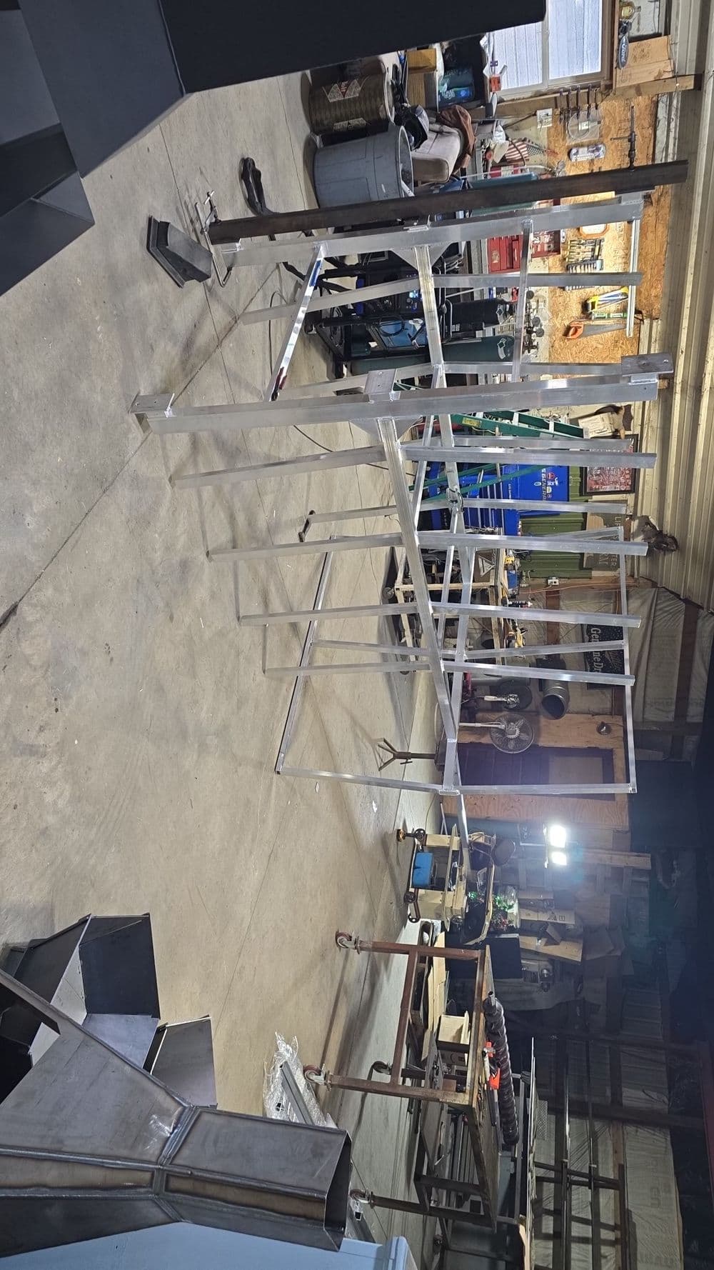 Metal frame construction in a workshop with tools and machinery in the background.