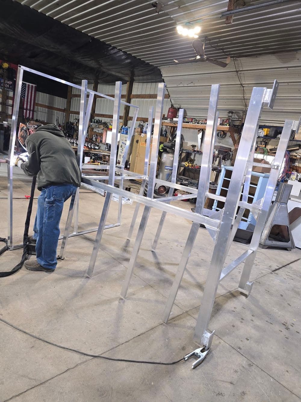 Welder assembling a metal frame in a workshop, showcasing aluminum construction.